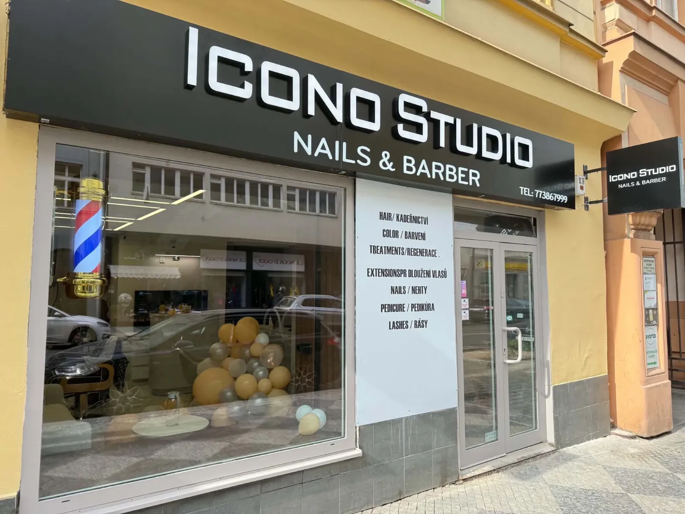 Výloha a černá cedule ICONO STUDIO Nails & Barber na Bělehradské 77 v Praze 2